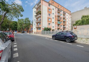 Ein mehrstöckiges Wohngebäude mit Balkonen, geparkten Autos und blauem Himmel.