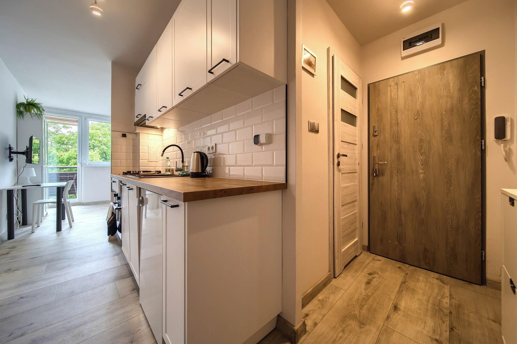 A modern kitchen with white cabinetry, a wooden countertop, and a built-in stove.