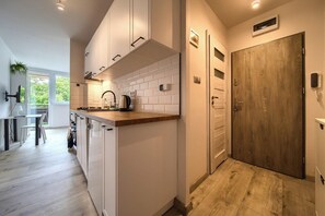 A modern kitchen with white cabinetry, a wooden countertop, and a built-in stove. - Park Skowroni Homely Studio (Wrocław)