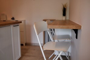 A kitchen with a wooden countertop, white chairs, and a white cabinet. - Park Skowroni Homely Studio (Wrocław)
