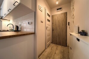 A narrow hallway with a wooden floor, a white tiled wall, and a wooden door. - Park Skowroni Homely Studio (Wrocław)