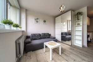 A modern living room with a grey sofa, a white coffee table, and a large mirror cabinet. - Park Skowroni Homely Studio (Wrocław)