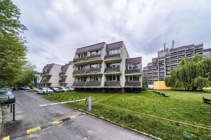 A multi-story residential building with balconies, a parking area, and a grassy courtyard. - Park Skowroni Homely Studio (Wrocław)