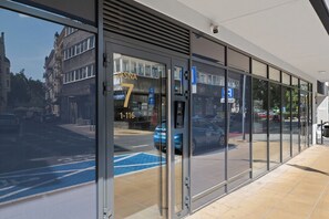 A modern building with large glass windows, a visible entrance, and a parking sign indicating a parking area. - Jasna City Center Apartment (Lublin)