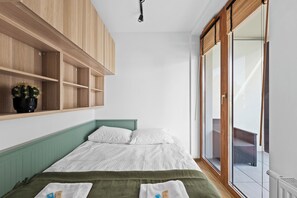 Une chambre à coucher avec un lit, une plante en pot et une porte-fenêtre coulissante donnant sur un balcon.
