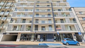 Ett hotell med flera våningar, balkonger, en entré i markplan och en parkeringsplats.
