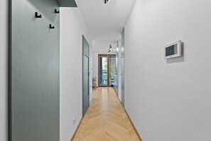 Un couloir doté d’un parquet en chevrons, de murs blancs et d’une porte donnant sur une pièce avec vue.