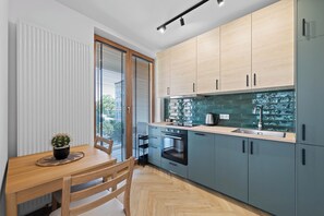 Eine moderne Küche mit einem Holztisch, einem eingebauten Backofen und hellen Schränken.