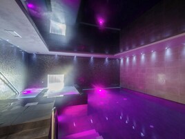Un spa moderno con una bañera grande, una camilla de masaje y una pared con textura.