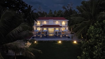 A large house with a swimming pool, surrounded by palm trees.