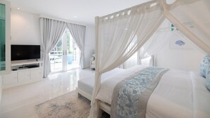 Une chambre à coucher avec un lit à baldaquin, un téléviseur posé sur un meuble et une grande fenêtre avec des rideaux.