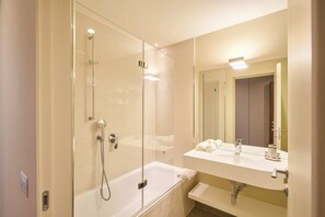 Ein modernes Badezimmer mit einer gläsernen Duschkabine, einer weißen Badewanne und einem Waschtisch mit Spiegel.