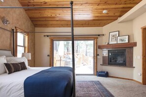 Un dormitorio con cama con dosel, chimenea y vistas a una terraza.