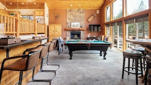 Un espacio interior acogedor con mesa de billar, bar y chimenea.