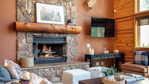 Una sala acogedora con chimenea de piedra, televisor montado y asientos cómodos.