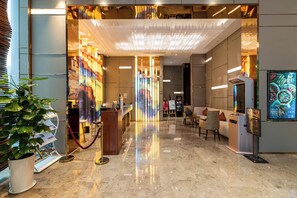 A hotel lobby with a reception desk, seating area, and a large digital screen displaying content. - Cheng Du Wifc Suites Yyc Preferred (Chengdu)