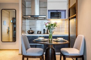 Una cocina moderna con comedor, que incluye una mesa redonda con dos sillas, un florero con flores y un microondas sobre la encimera.