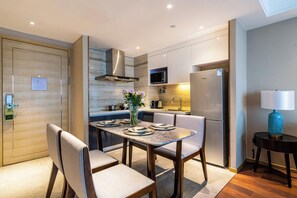 A modern kitchen with a dining area, equipped with stainless steel appliances, a microwave, and a refrigerator. - Cheng Du Wifc Suites Yyc Preferred (Chengdu)