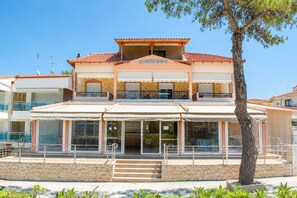 A two-story building with a covered outdoor area, a stone facade, and a sign that reads 'AIONNEOS'. - Dionysos Hotel (Kassandra)