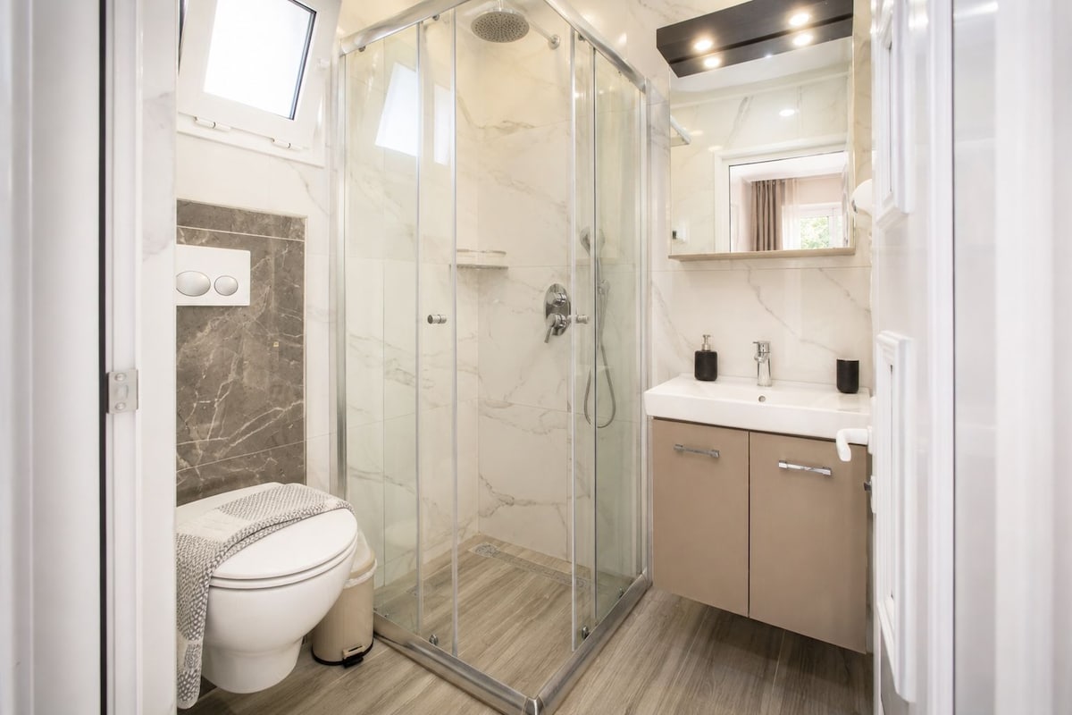 Un baño moderno con ducha acristalada, inodoro y tocador con espejo.