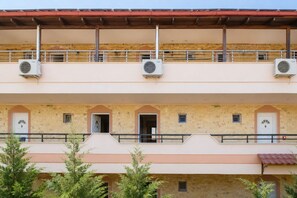 A multi-story building with balconies, air conditioning units, and a stone facade. - Dionysos Hotel (Kassandra)