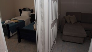 A hotel room with a bed, a sofa, and a door. - Dionysos Hotel (Kassandra)