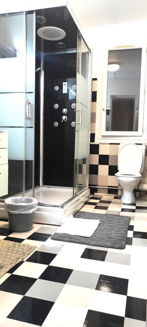 Un baño con ducha de vidrio, inodoro y lavamanos.