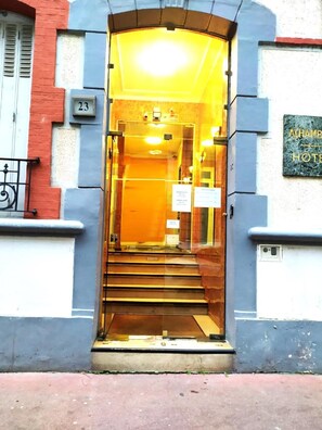 A hotel entrance with a glass door, a staircase leading inside, and a sign indicating the hotel's name. - Hotel Residence Saint Ouen (Saint-Ouen)