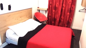 A single bed with a wooden headboard, a red chair, and a red curtain. - Hotel Residence Saint Ouen (Saint-Ouen)