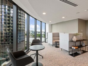 A modern office space with a large window, a round table, and a sofa. - Gorgeous Wide View 2BR High Level /Sunset/Casino (Brisbane)
