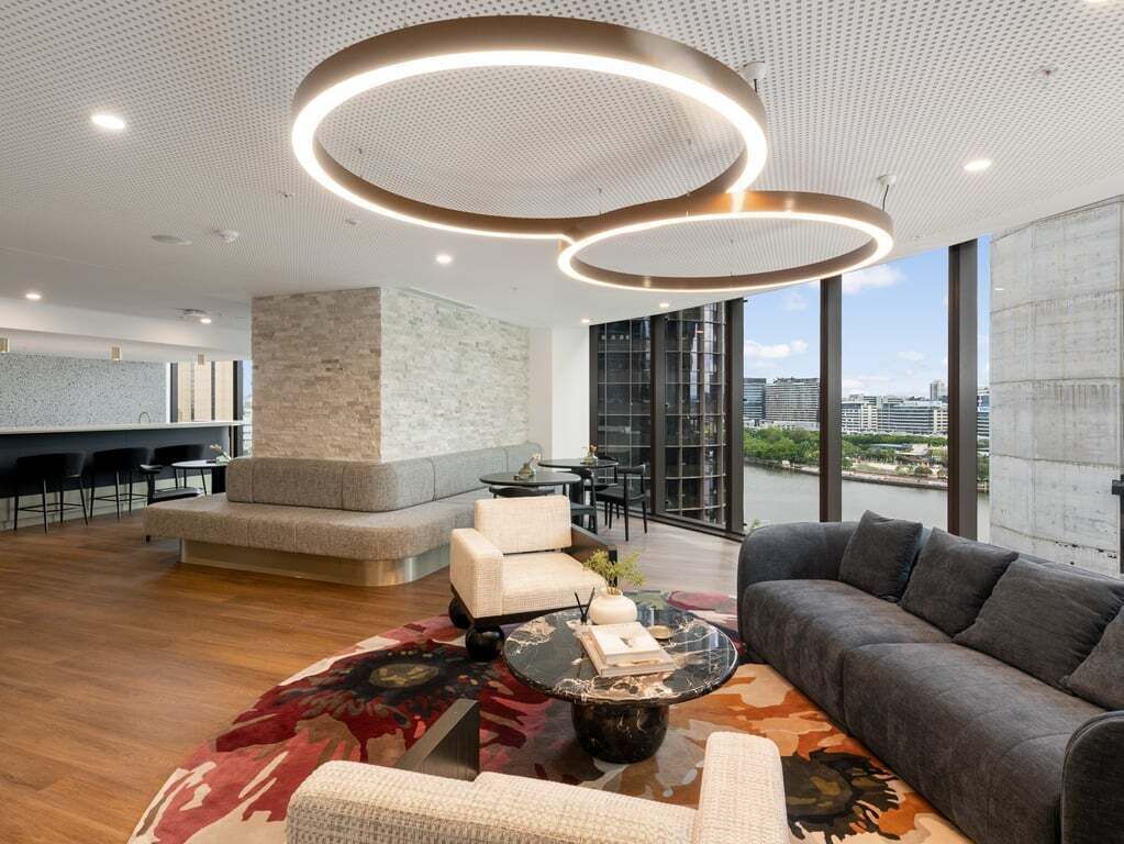 A modern lounge area with a sofa, armchairs, a coffee table, and a view of the city.