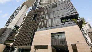 A modern high-rise building with a curved facade, large windows, and a prominent central tower. - Gorgeous Wide View 2BR High Level /Sunset/Casino (Brisbane)