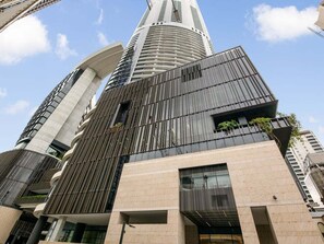 A modern high-rise building with a curved facade, large windows, and a prominent central tower. - Gorgeous Wide View 2BR High Level /Sunset/Casino (Brisbane)