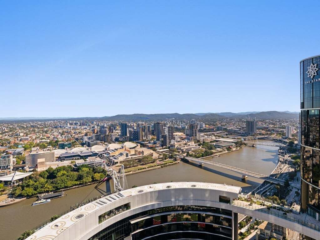 A cityscape with a prominent bridge, a river, and a modern building with a glass facade.