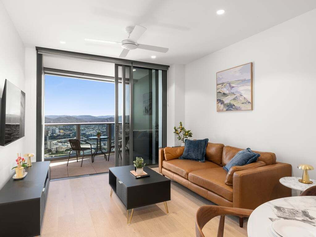 Ein modernes Wohnzimmer mit Sofa, Couchtisch und einem Balkon mit Blick auf die Stadt.