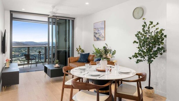 A modern dining area with a round table, chairs, and a view through large windows. - Gorgeous Wide View 2BR High Level /Sunset/Casino (Brisbane)