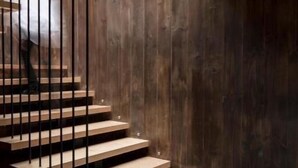 A staircase with wooden steps and metal railings, leading to a dark wooden wall.