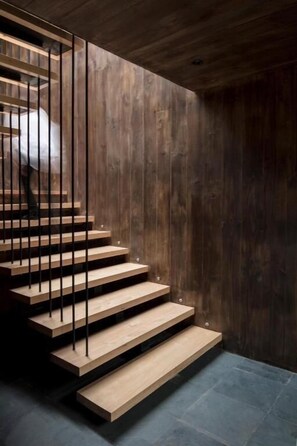 A staircase with wooden steps and metal railings, leading to a dark wooden wall.