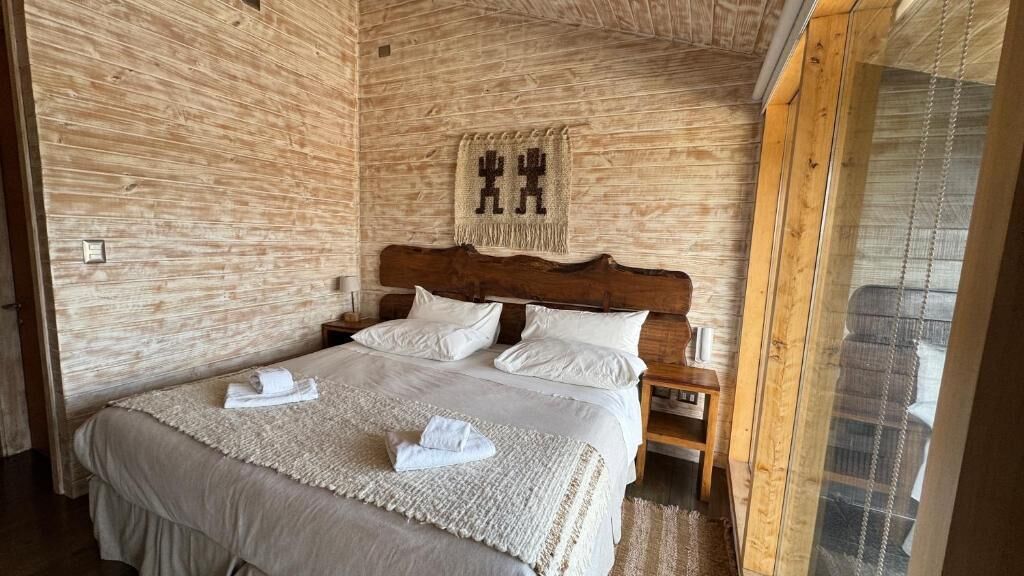 Una habitación con una cama grande, cabecera de madera y un tapiz colgado en la pared.