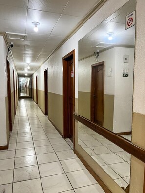 A long hallway with doors on both sides, a no-smoking sign, and a light fixture on the ceiling. - Hotel Avenida (Belém)