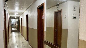 Um corredor longo com portas em ambos os lados, um aviso de proibido fumar e um aparelho de iluminação no teto.