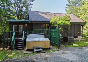 Eine Holzhütte mit Whirlpool, einer Terrasse und einem überdachten Außenbereich.