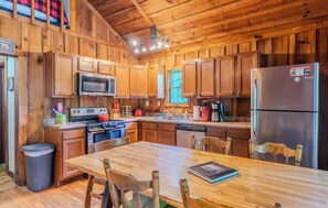 A wooden cabin-style kitchen with a central island, stainless steel appliances, and wooden cabinetry. - Pine Cove - Hot Tub - Pet Friendly - Large Yard (Campton)