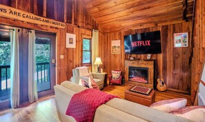 L’intérieur d’un chalet accueillant, doté d’une cheminée, d’un téléviseur et d’un coin salon confortable.