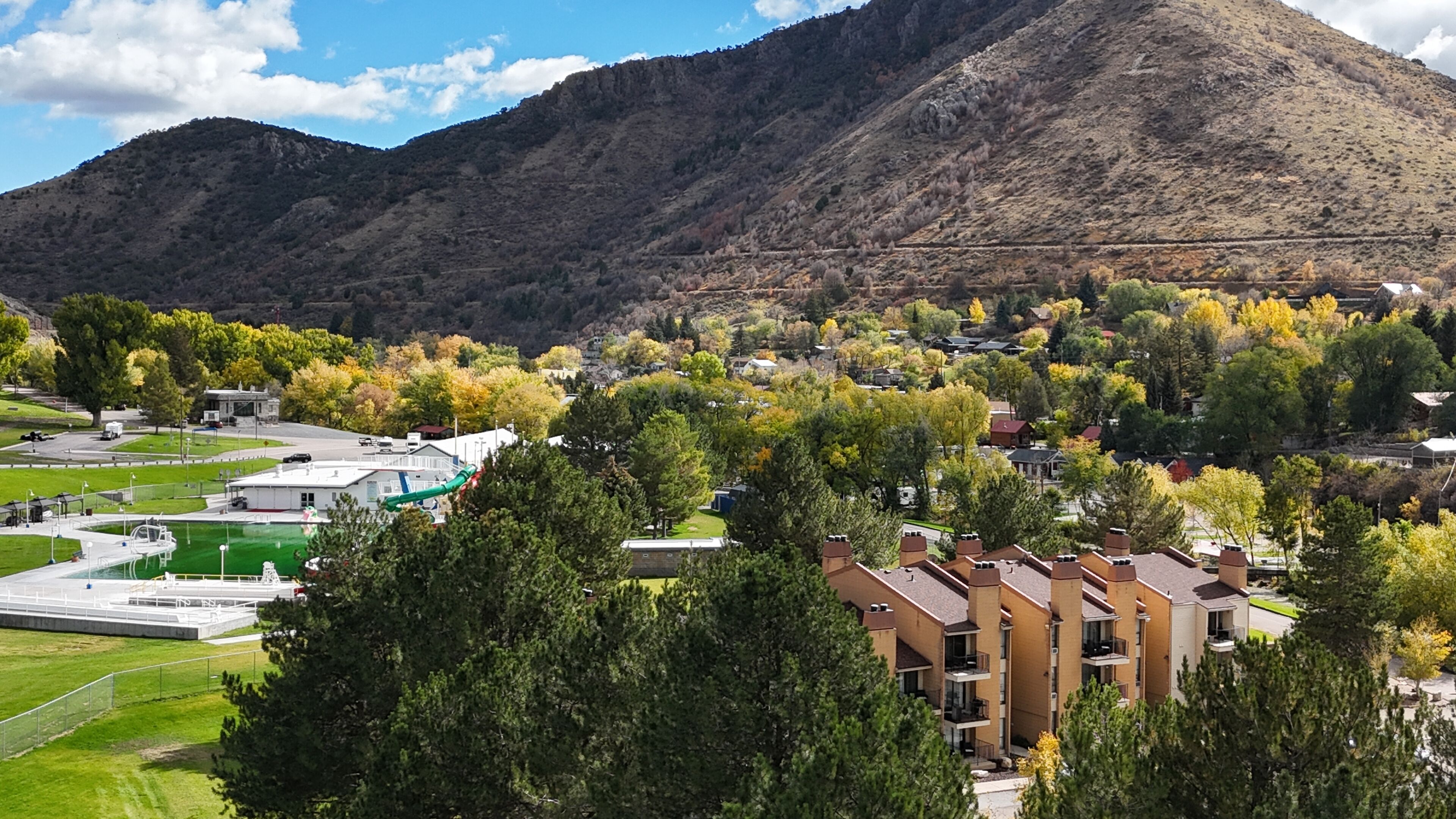 A residential area with houses, a green sports field, and a mountain in the background.