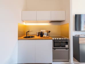 A compact kitchenette with a built-in oven, a sink, and a coffee maker. - Cosy 2-Br Apartment - Cannes City Centre (Cannes)