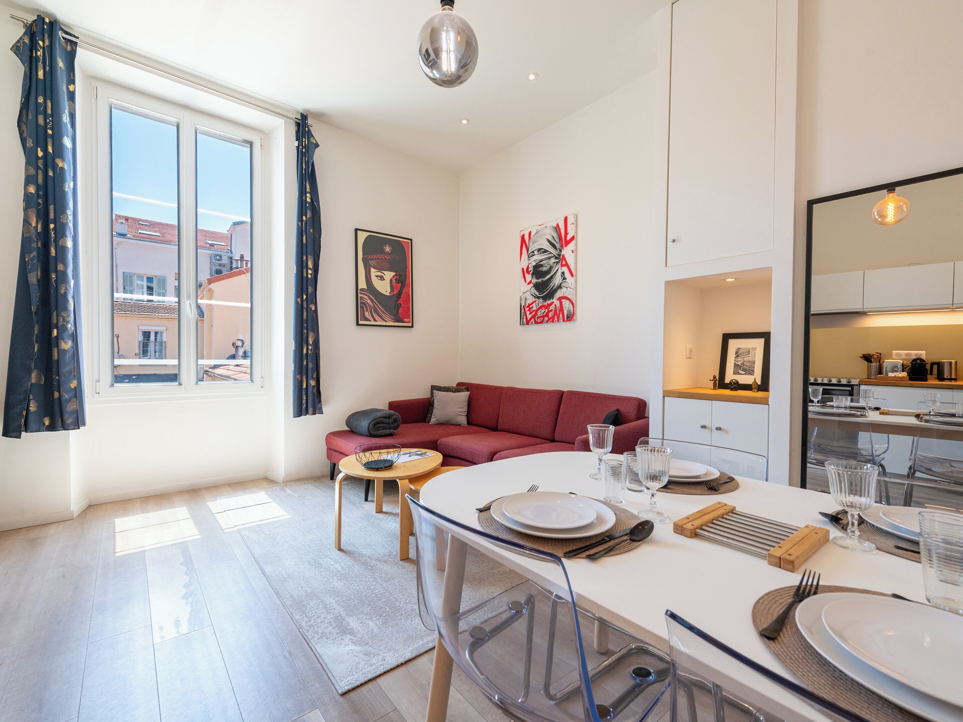 A modern living space with a dining area, a sofa, and a kitchen.