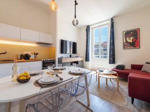 A modern kitchen with a dining area, a flat-screen TV, and a red sofa. - Cosy 2-Br Apartment - Cannes City Centre (Cannes)