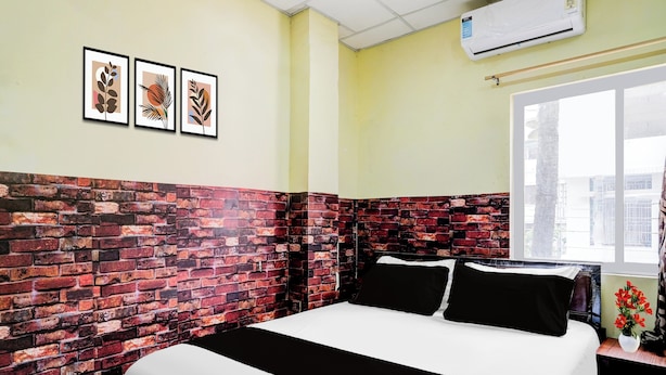 Una habitación con pared de ladrillo decorativa, cama con ropa de cama blanco y negro, ventana con vistas, y tres obras de arte enmarcadas en la pared.