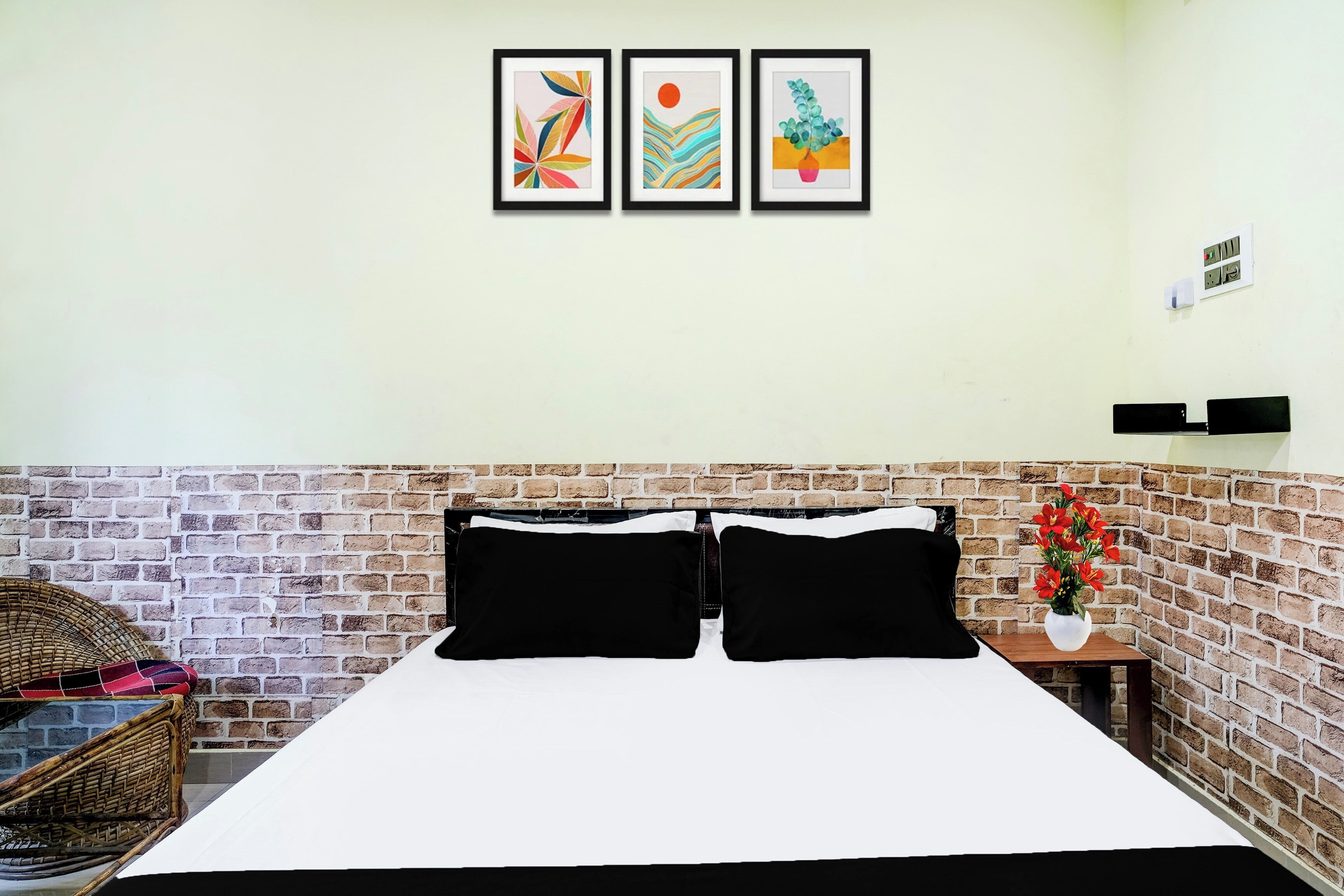 Una habitación de hotel con una pared de ladrillo, una cama con ropa de cama blanco y negro, y tres obras de arte enmarcadas en la pared.